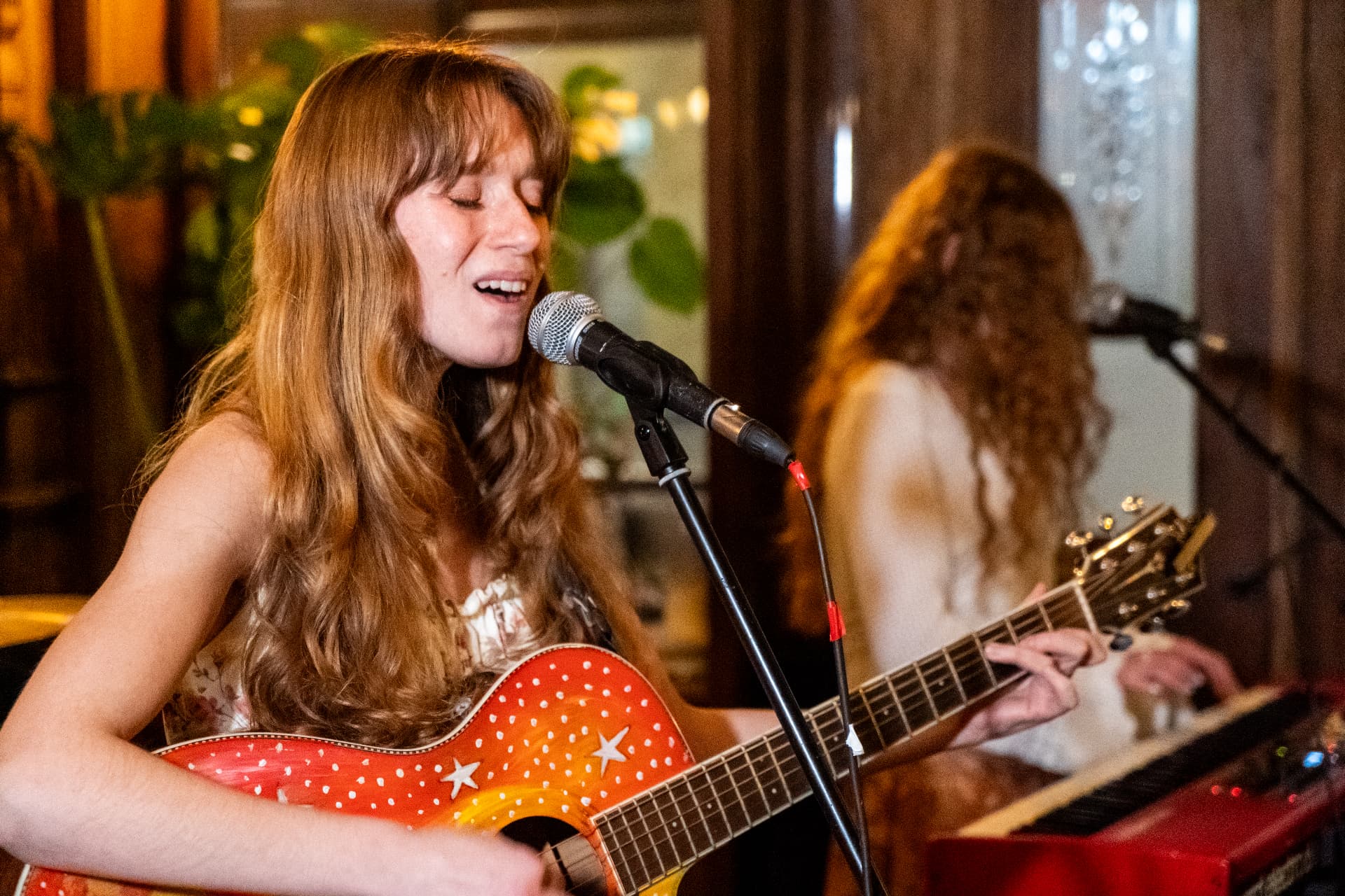 Singer playing a red acoustic guitar